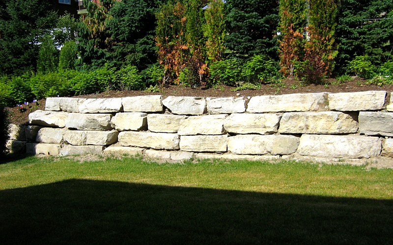 Completed armourstone retaining wall with cedar landscaping
