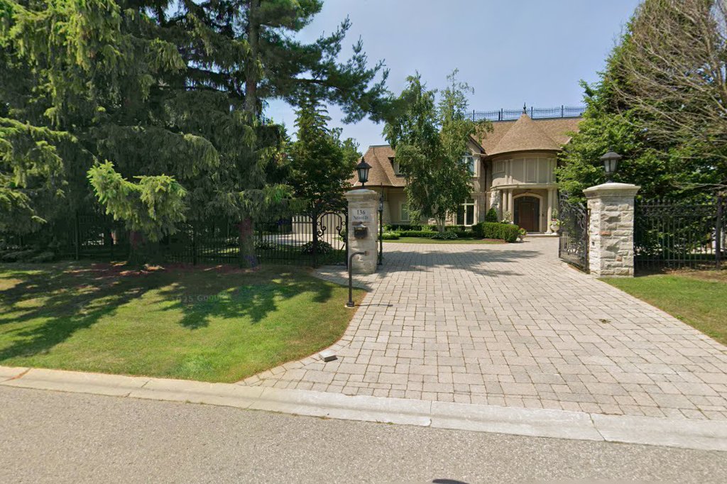 136 National Drive – Estate entrance with stone pillars, iron gates, and brick driveway