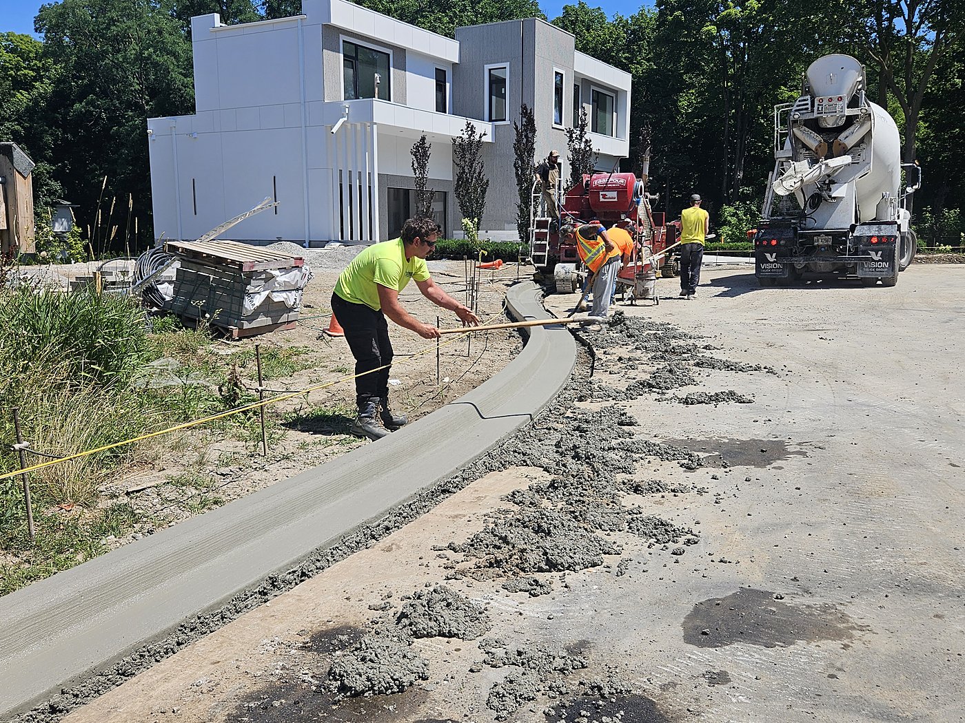 Workers pouring concrete curb with cement truck at Donna Mae Estates