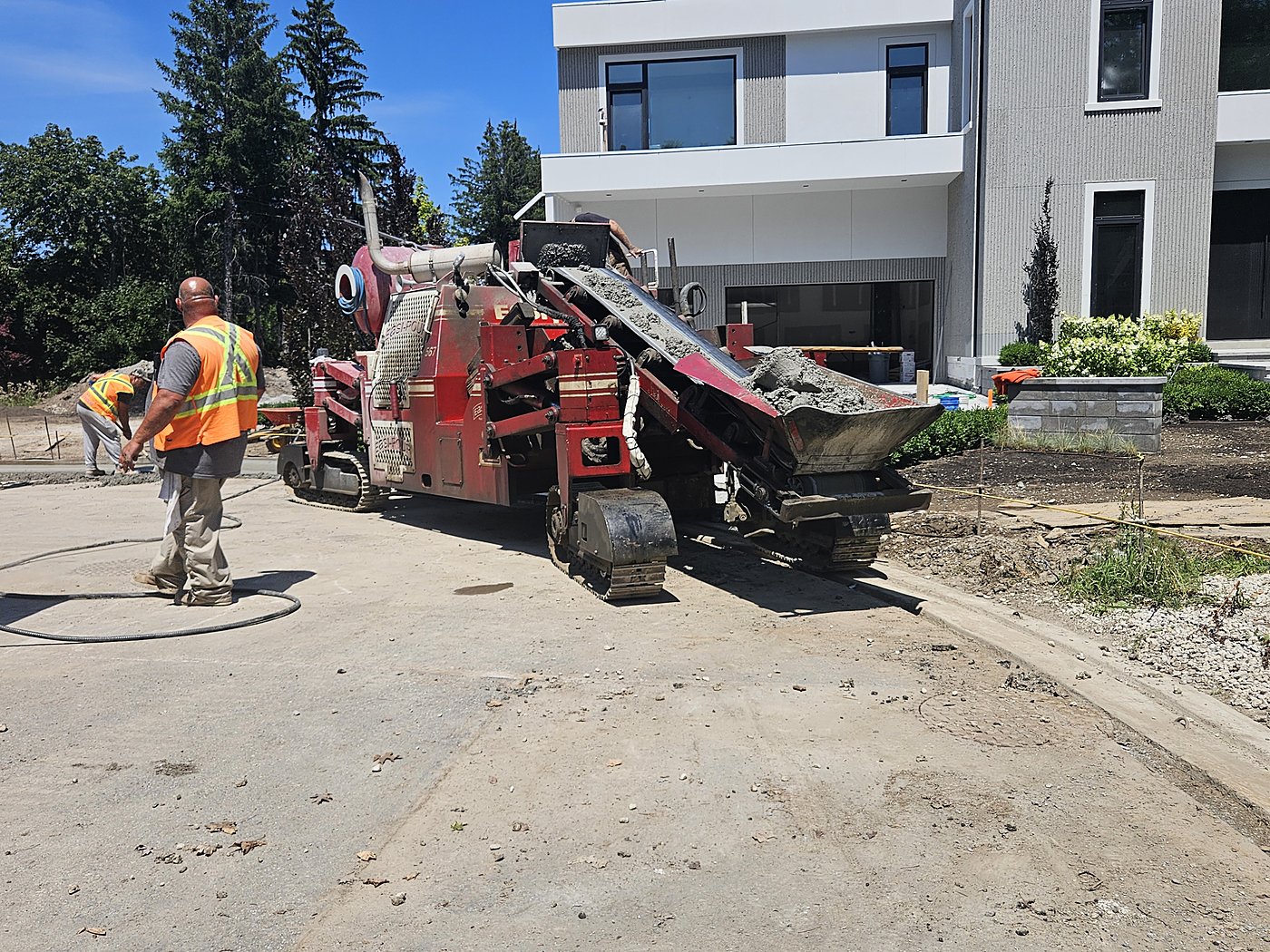 Curb machine with workers during roadway construction
