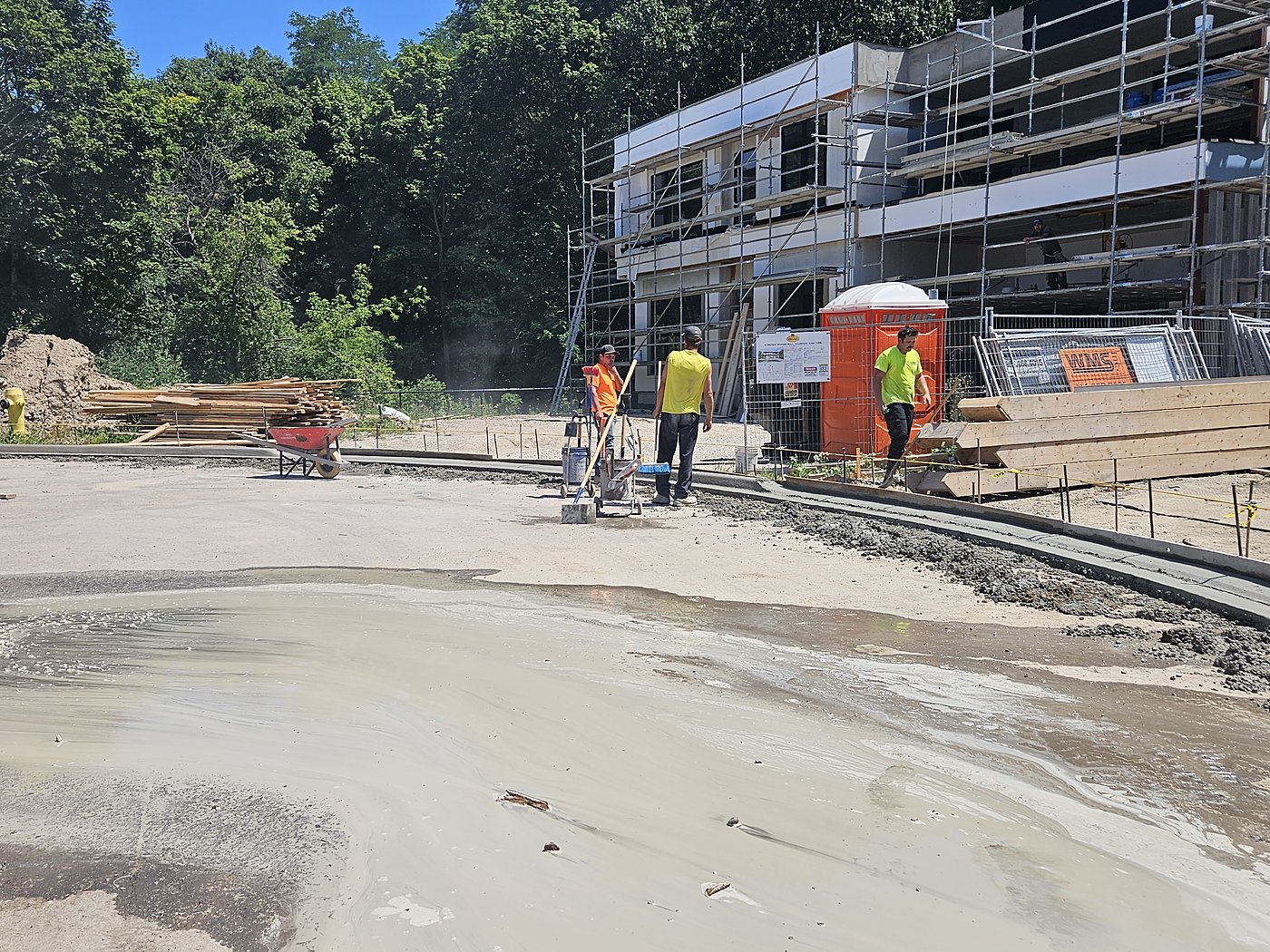 Workers with curb machine near new home under construction