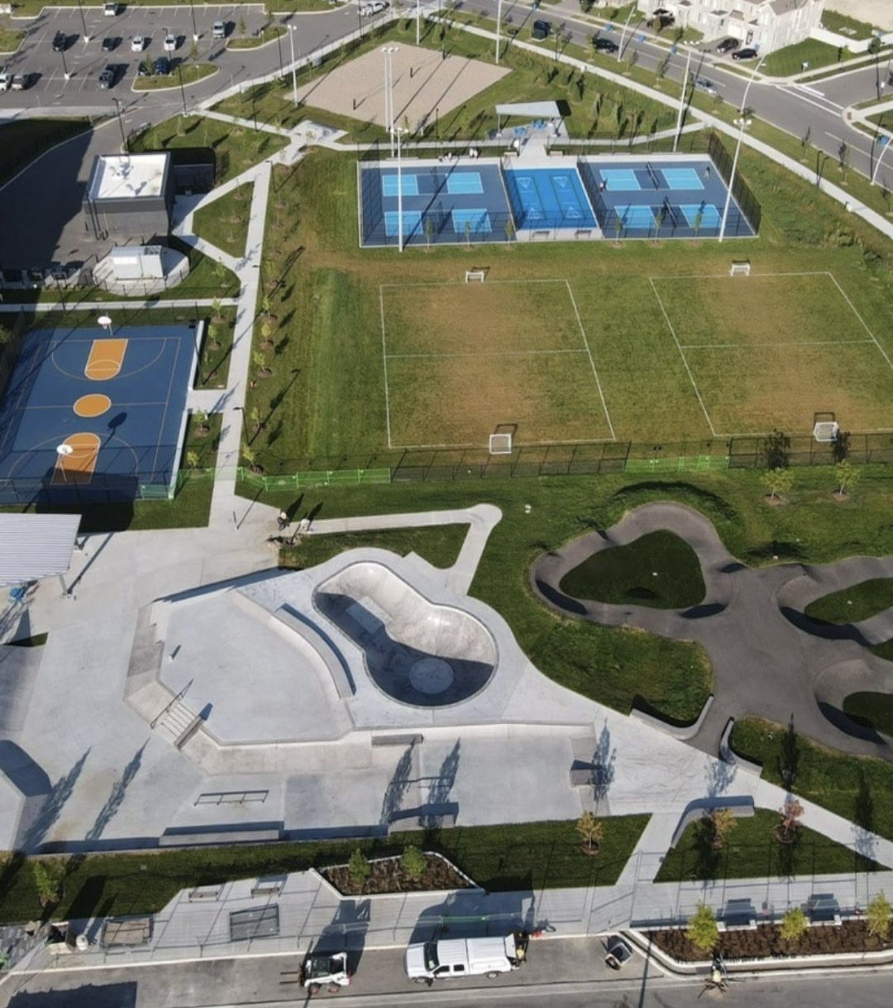 East Gwillimbury Health and Active Living Plaza – Drone view of pickleball courts, soccer fields, basketball court, skate park and pump track with the parking lot beyond
