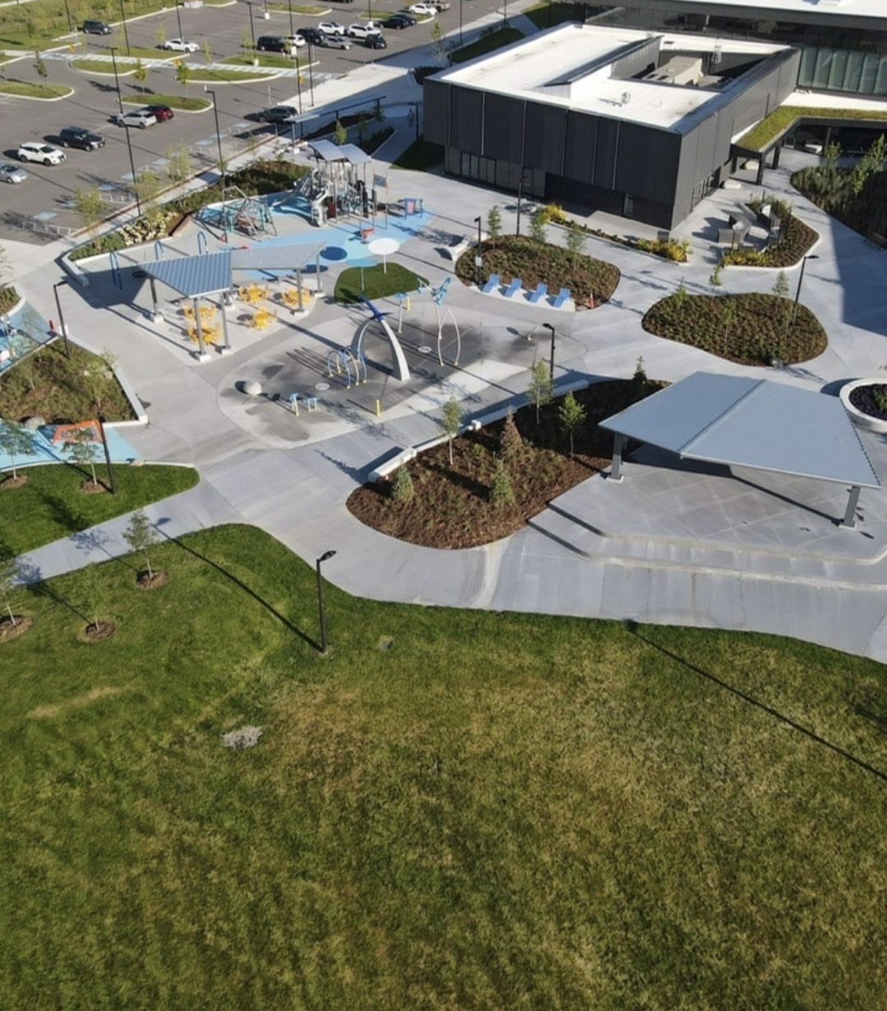 East Gwillimbury Health and Active Living Plaza – Drone view of the plaza with picnic pavilions, splash pad, playground and the community centre, parking lot beyond
