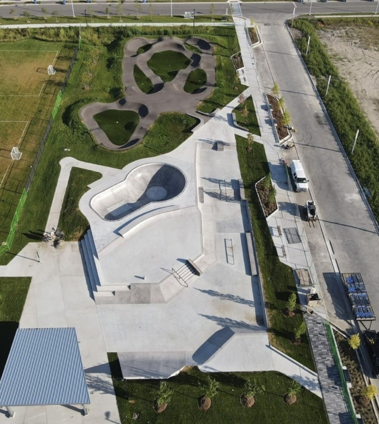East Gwillimbury Health and Active Living Plaza – Drone view of the concrete skate park, asphalt pump track and picnic shelter beside the soccer fields