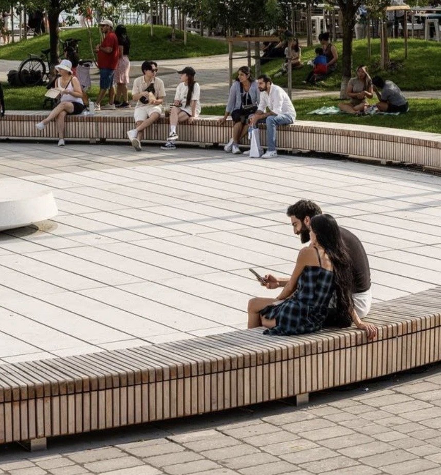 Harbourfront Centre Community Square – People seated on curved timber slat benches around the paved plaza