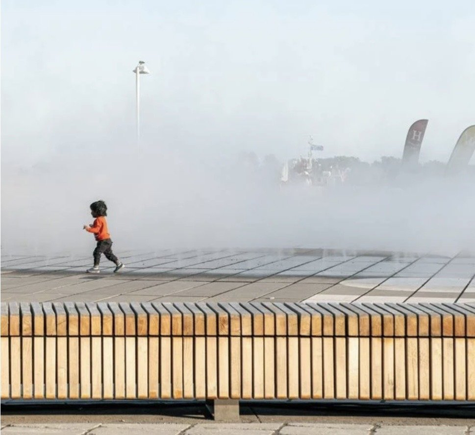 Harbourfront Centre Community Square – Child running through fog on the plaza behind a timber slat bench