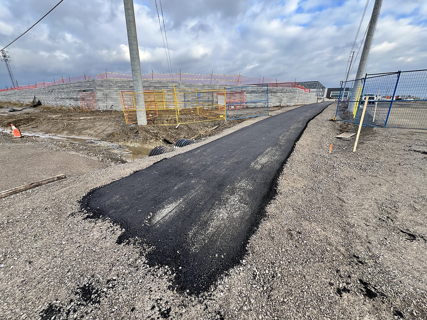 Fresh asphalt section with yellow safety fencing