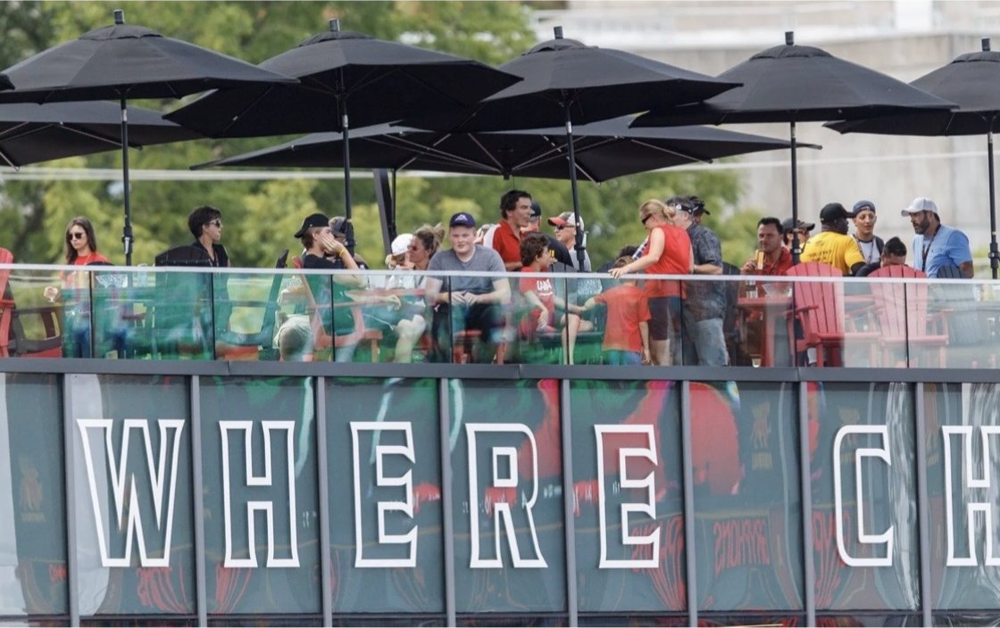 University of Guelph – Alumni Stadium – Spectators on the pavilion rooftop patio under black umbrellas above the Where Champions Are Built signage